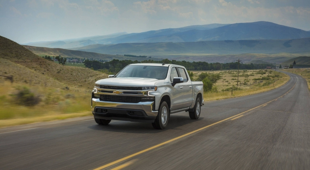 A silver 2021 Chevy Silverado 1500 LT driving down a country highway.