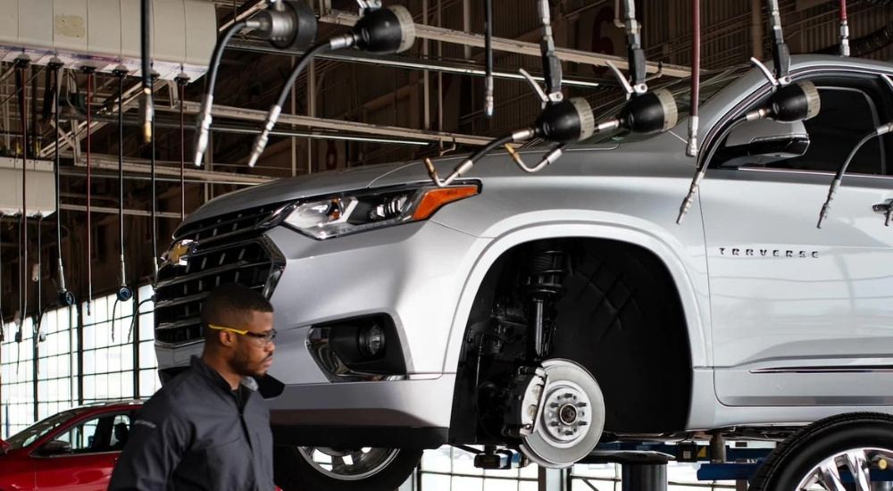 A silver 2020 Chevy Traverse is shown being serviced on a lift.