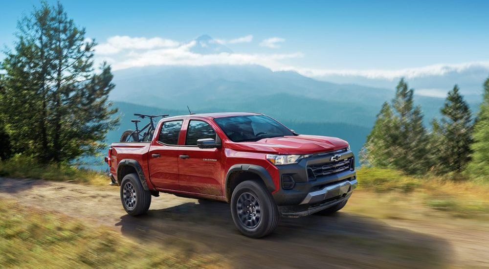 A red 2023 Chevy Colorado Trail Boss is shown off-road after leaving a Booneville Chevy dealer.