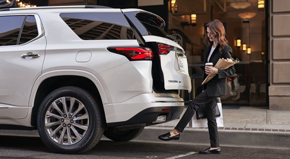 A person is shown opening the liftgate on a white 2023 Chevy Traverse after shopping.