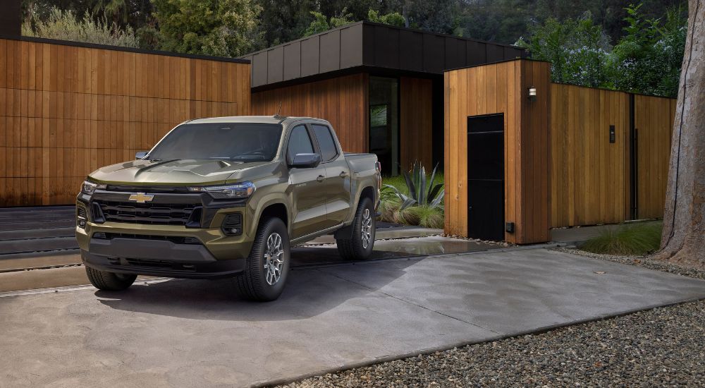 A green 2023 Chevy Colorado LT is shown in front of a modern house after leaving a Chevy dealer near Ripley.