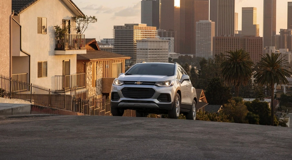 A silver 2022 Chevy Trax is shown driving uphill after visiting a used Chevy dealer.