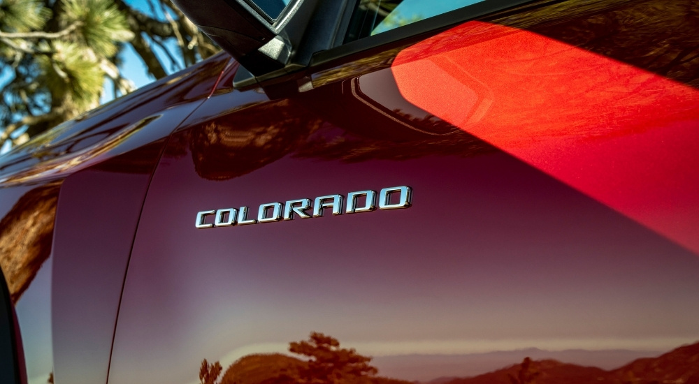 A close-up shows the door badge on a red 2023 Chevy Colorado Trail Boss.