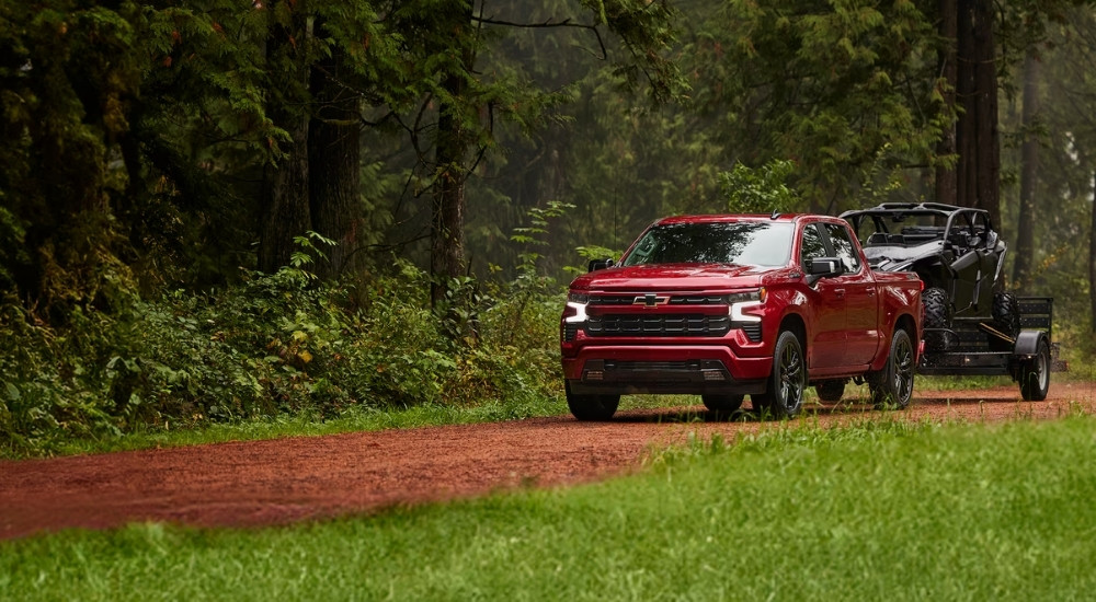 A red 2024 Chevy Silverado 1500 RST is shown towing an ATV.