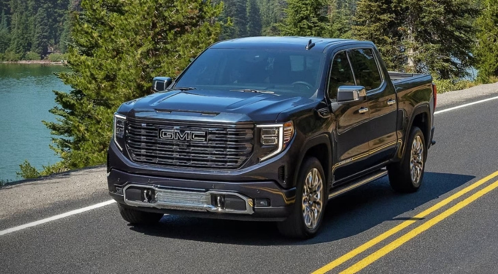 A black 2024 GMC Sierra 1500 Denali is shown passing a lake after looking at trucks for sale near Booneville.