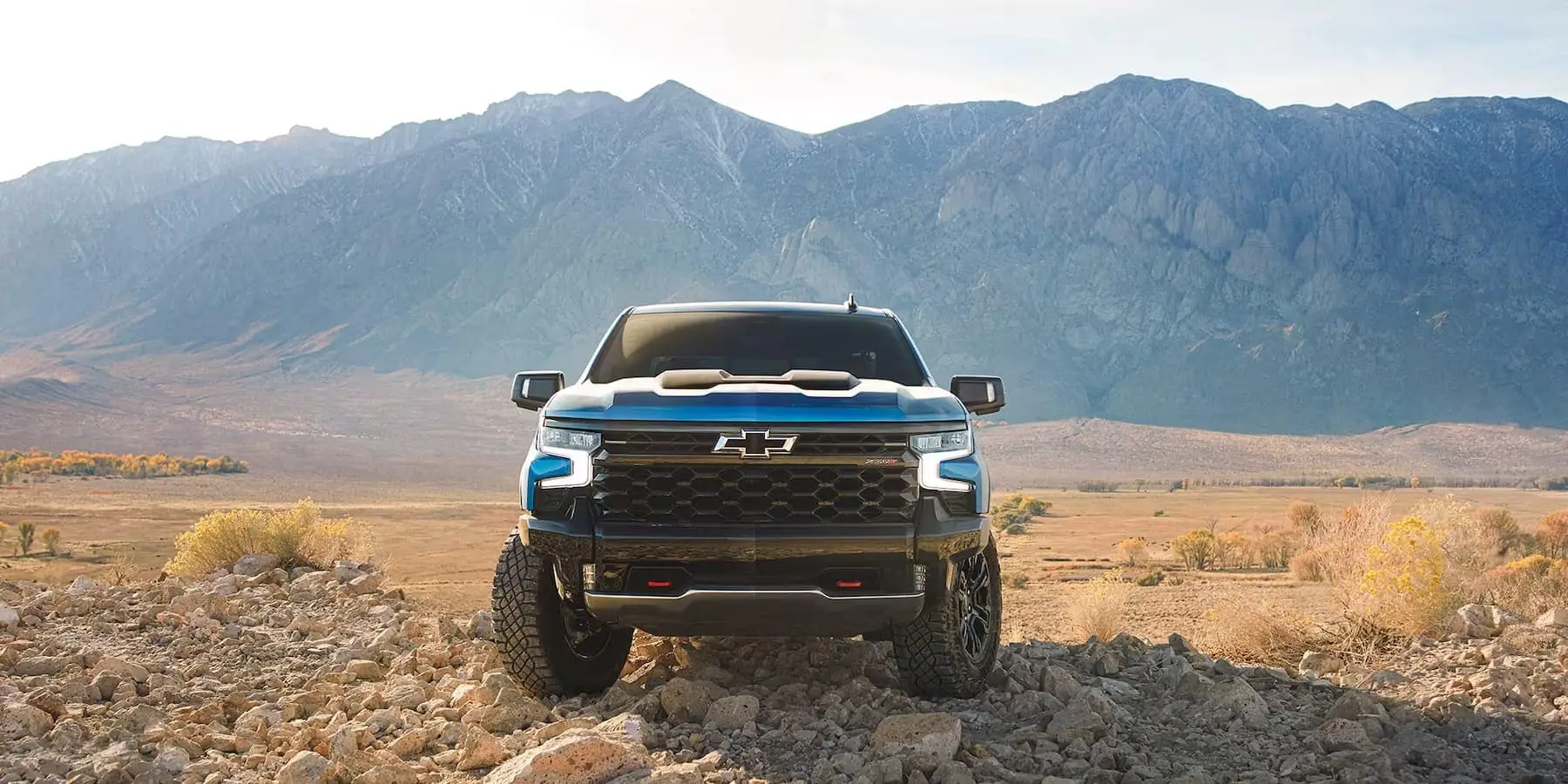 A blue 2024 Chevy Silverado 1500 ZR2 is shown parked on rocks.