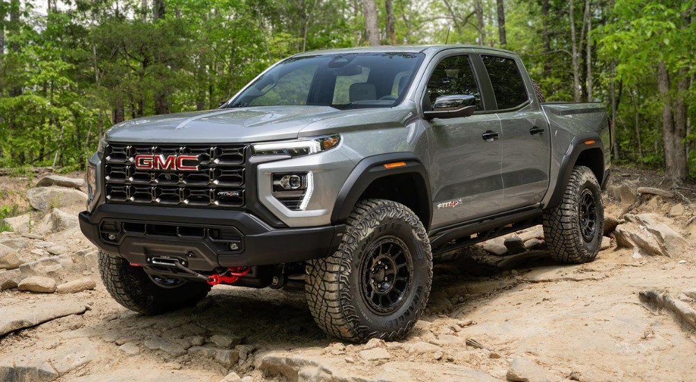 A silver 2025 GMC Canyon AT4X AEV is parked off-road.