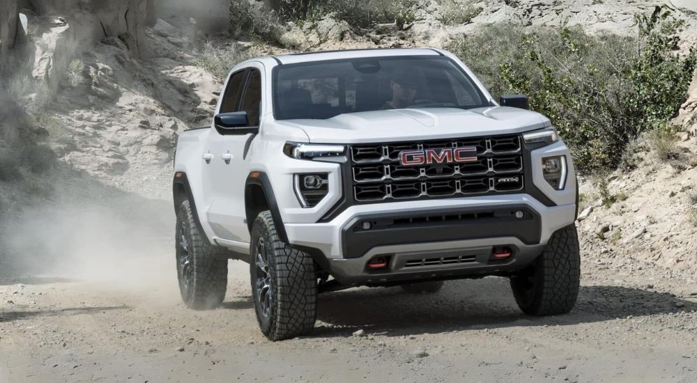 White 2025 GMC Canyon AT4 driving down a trail from a dealer with GMC trucks for sale near Ripley.