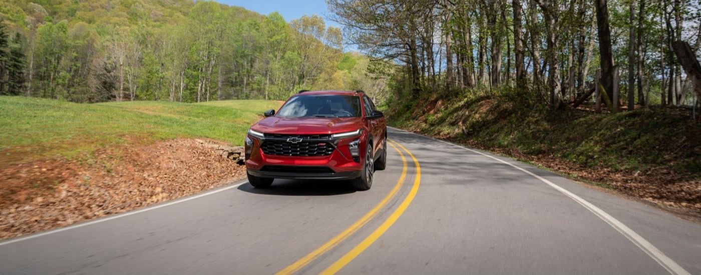 A red 2024 Chevy Trax RS shown driving a paved road.