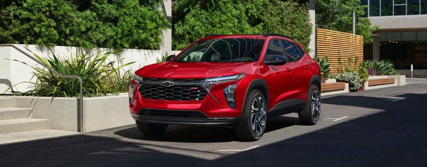 A red 2026 Chevy Trax RS parked by bushes.