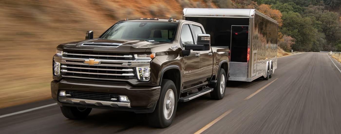 A black 2021 Chevy Silverado 2500 HD High Country towing a trailer.