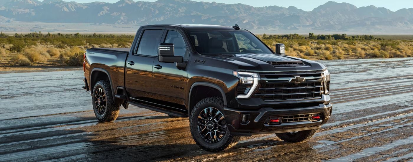 A black 2026 Chevy Silverado 2500 HD Z71 Stars and Steel parked on a wet dirt road.