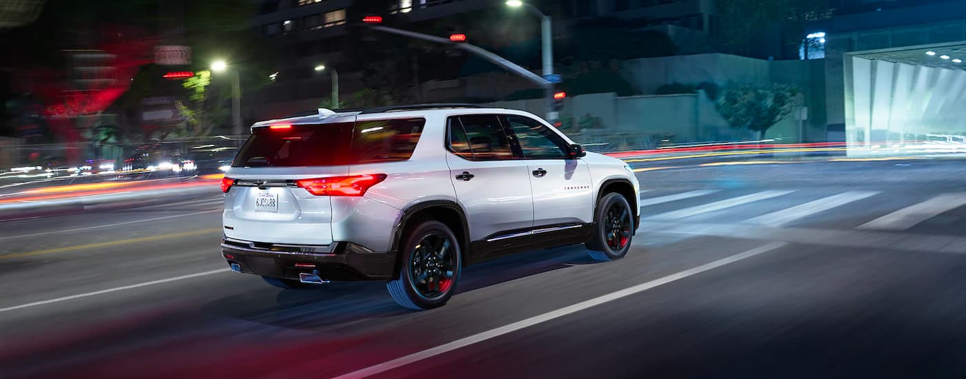 A white 2022 Chevy Traverse is shown driving through an intersection at night.