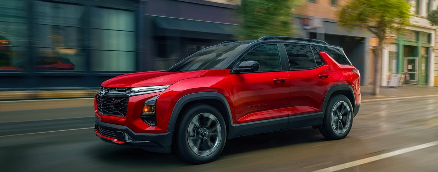 Red 2025 Chevy Equinox RS driving down a city street.