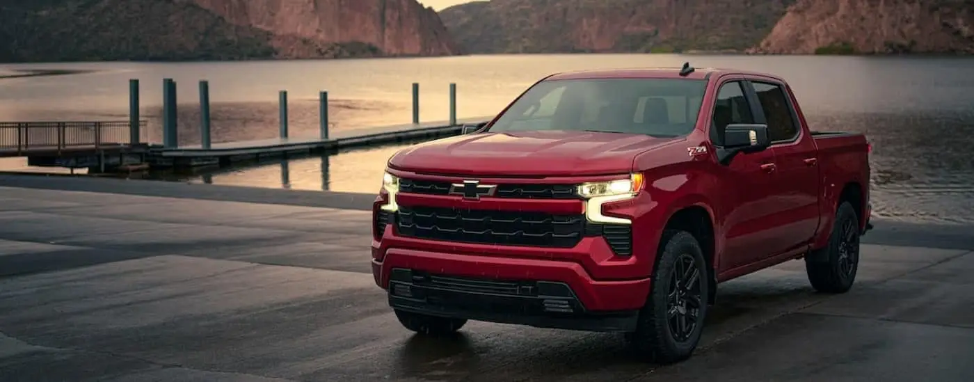 A red 2024 Chevy Silverado 1500 RST is shown parked near a dock.