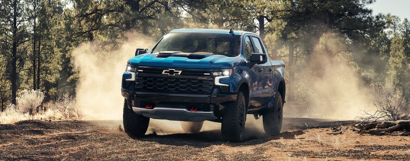 A blue 2025 Chevy Silverado 1500 ZR2 is shown driving to a Chevy dealer in Corinth, MS.