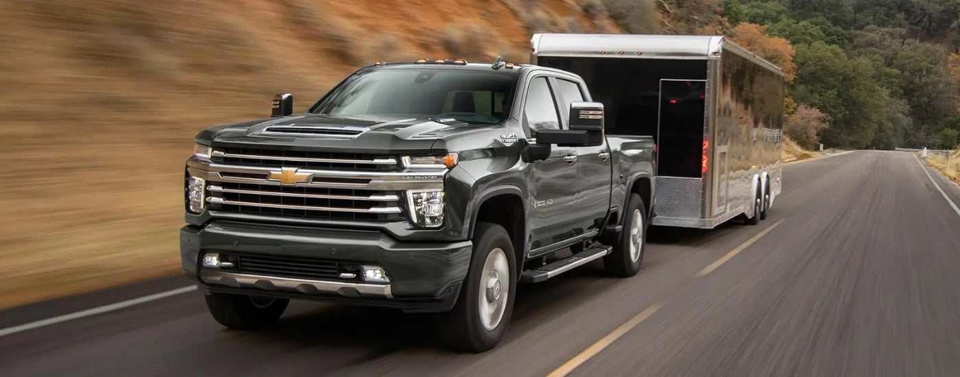A black 2022 Chevy Silverado 2500 HD High Country is shown from the front towing a closed trailer.