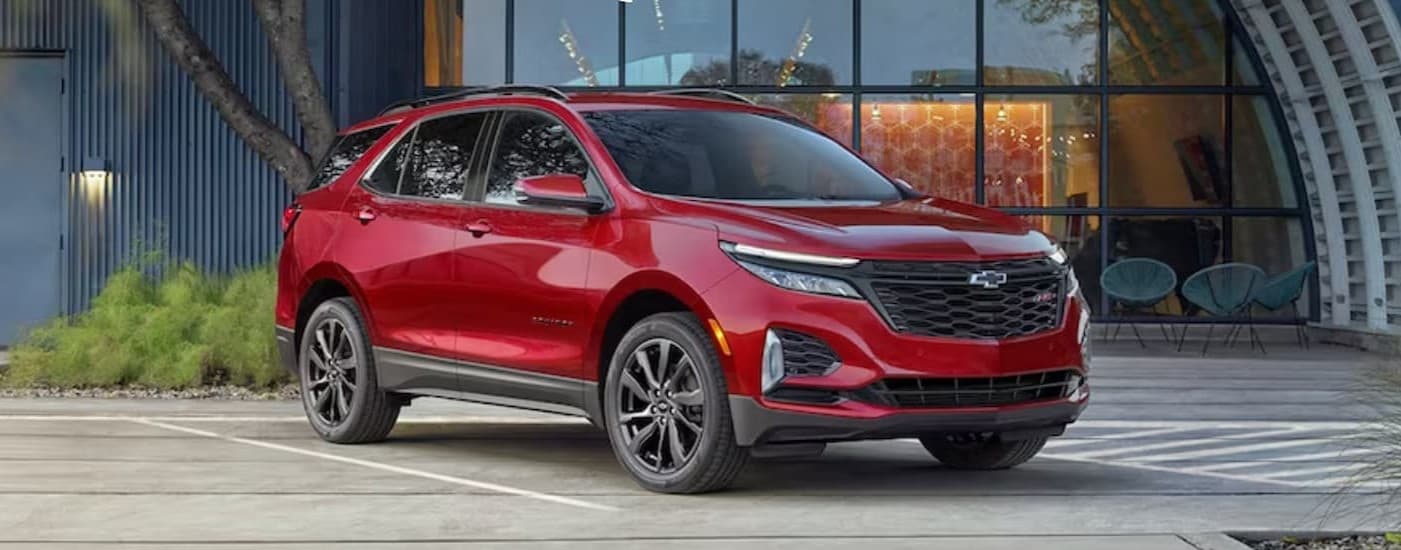 A red 2025 Chevy Equinox RS parked near a hangar.