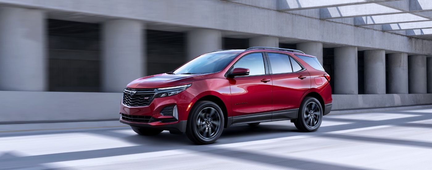 A red 2022 Chevy Equinox is shown from the side while driving after leaving a dealer that offers Chevy financing.