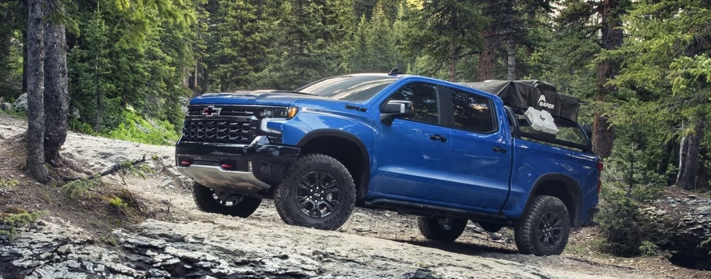 A blue 2024 Chevy Silverado 1500 ZR2 is shown off-road.