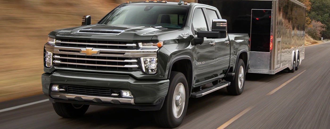 A black 2023 Chevy Silverado 2500HD is shown towing a black enclosed trailer.
