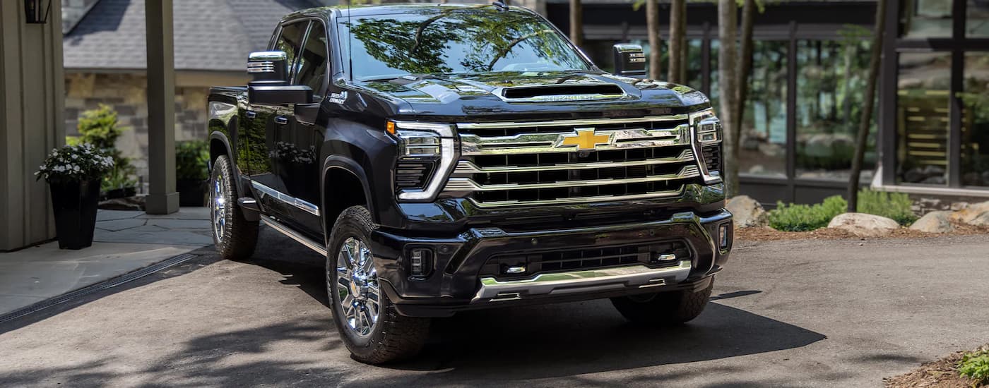 A black 2024 Chevy Silverado 3500HD High Country is shown parked in a driveway.