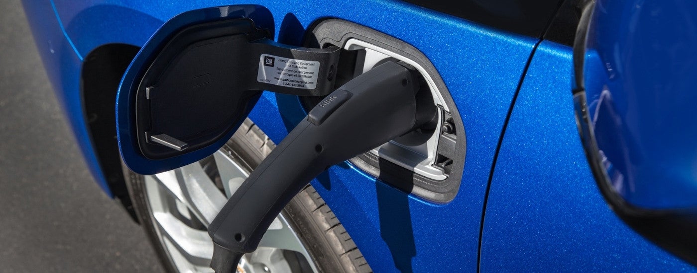 A close-up shows a blue 2016 Chevy Volt charging at an electric car dealership in MS.