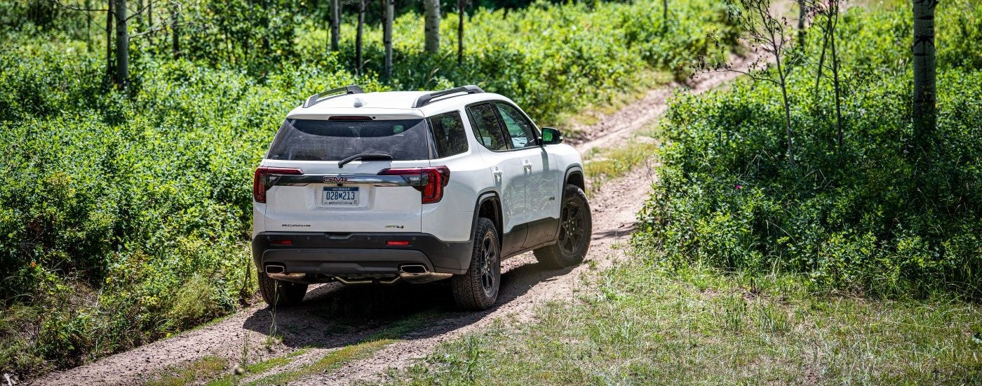 A white 2020 GMC Acadia AT4 is shown from the rear at an angle.