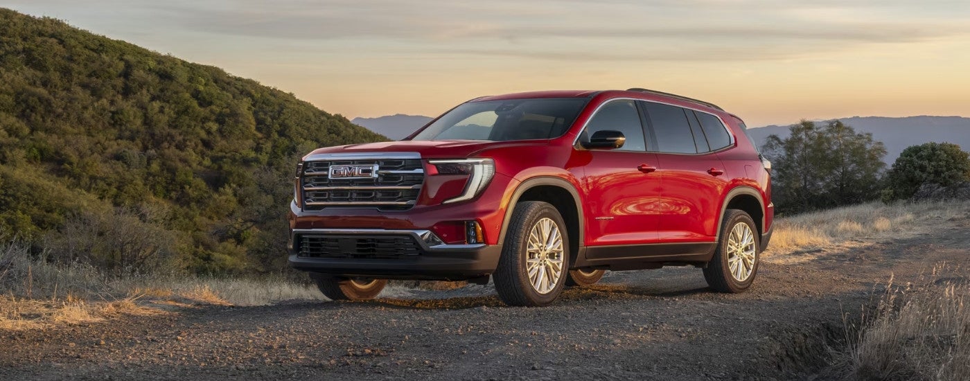A red 2025 GMC Acadia is shown driving to a GMC Acadia dealer.