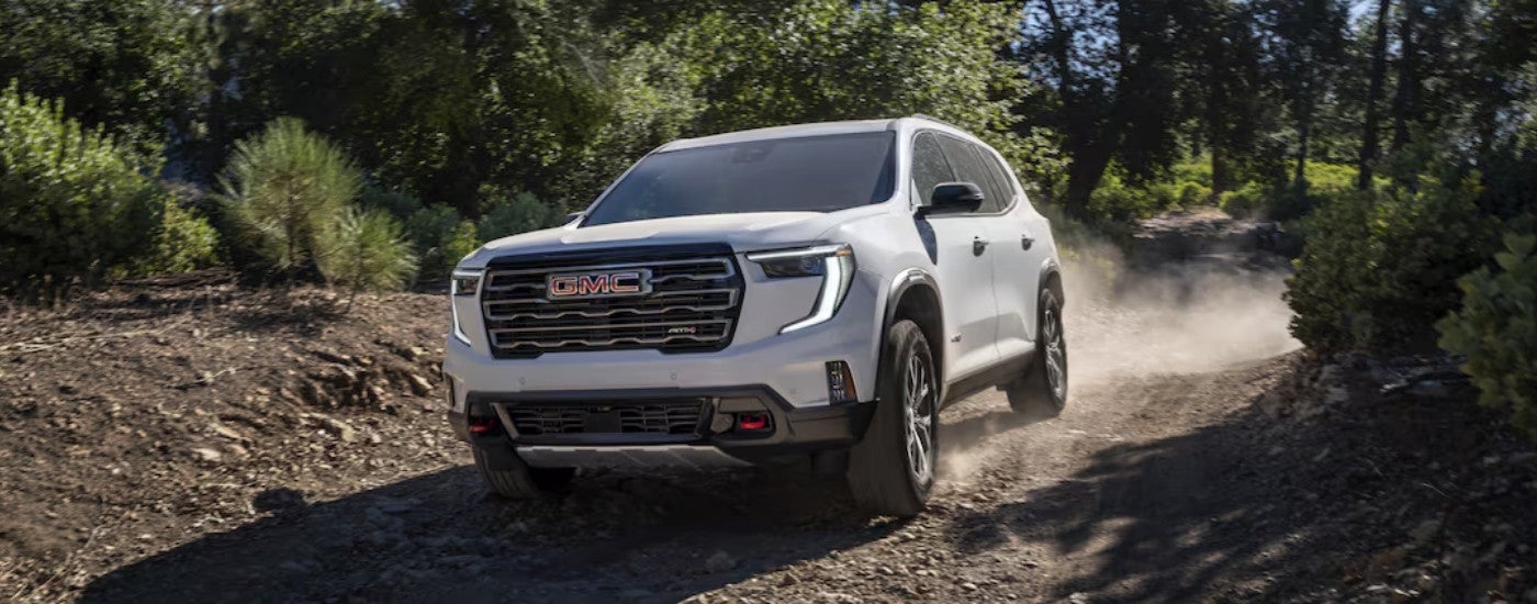 A white 2025 GMC Acadia AT4 kicking up dust.