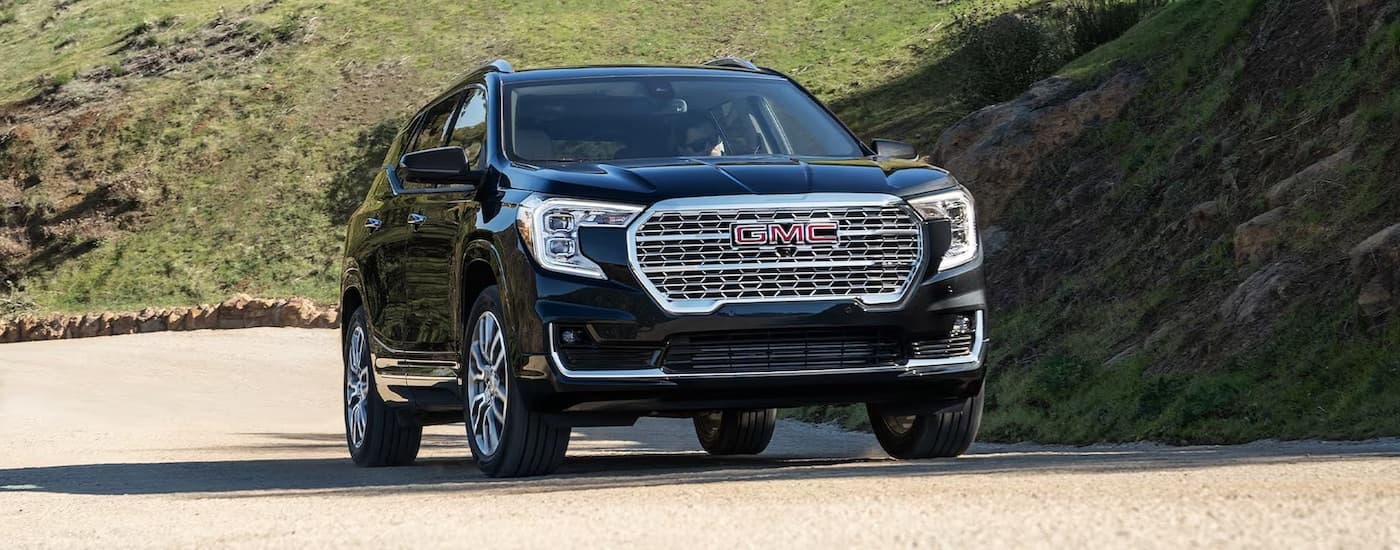 A black 2024 GMC Terrain Denali driving down a winding road.