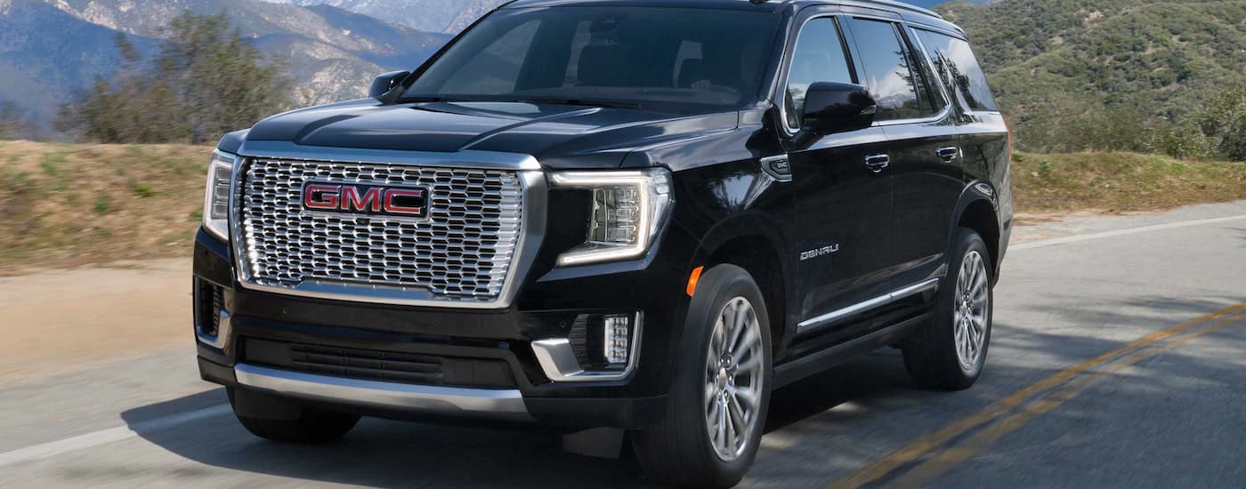 A black 2023 GMC Yukon Denali Ultimate is shown driving on an open road after leaving a Ripley GMC dealer.