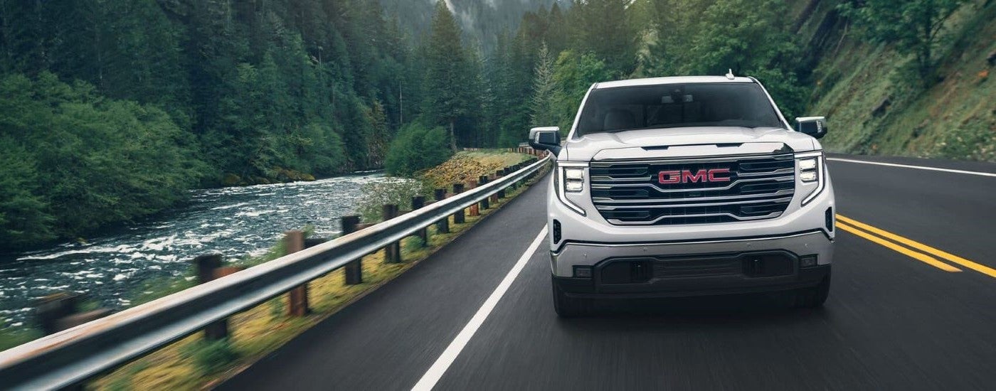 A white 2024 GMC Sierra 1500 Pro is shown driving on a highway after viewing a GMC Sierra for sale in Corinth.