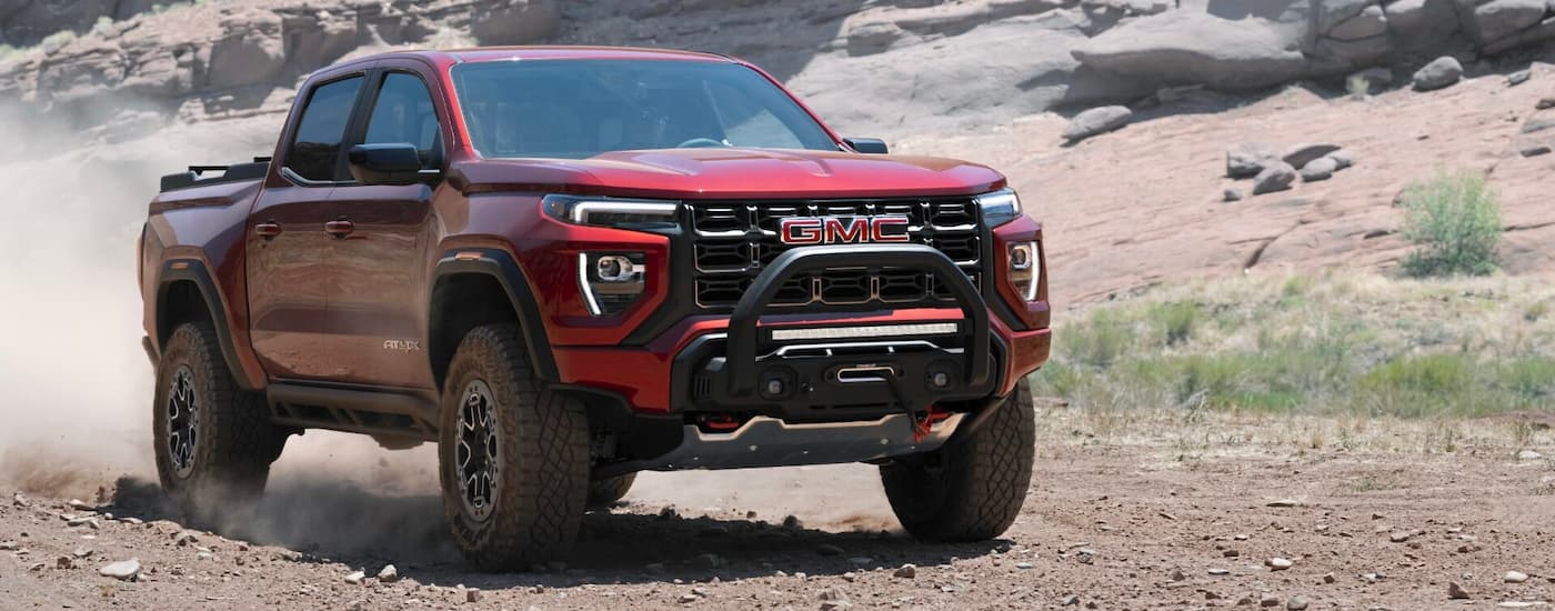 A red 2023 GMC Canyon AT4X is shown driving off-road.