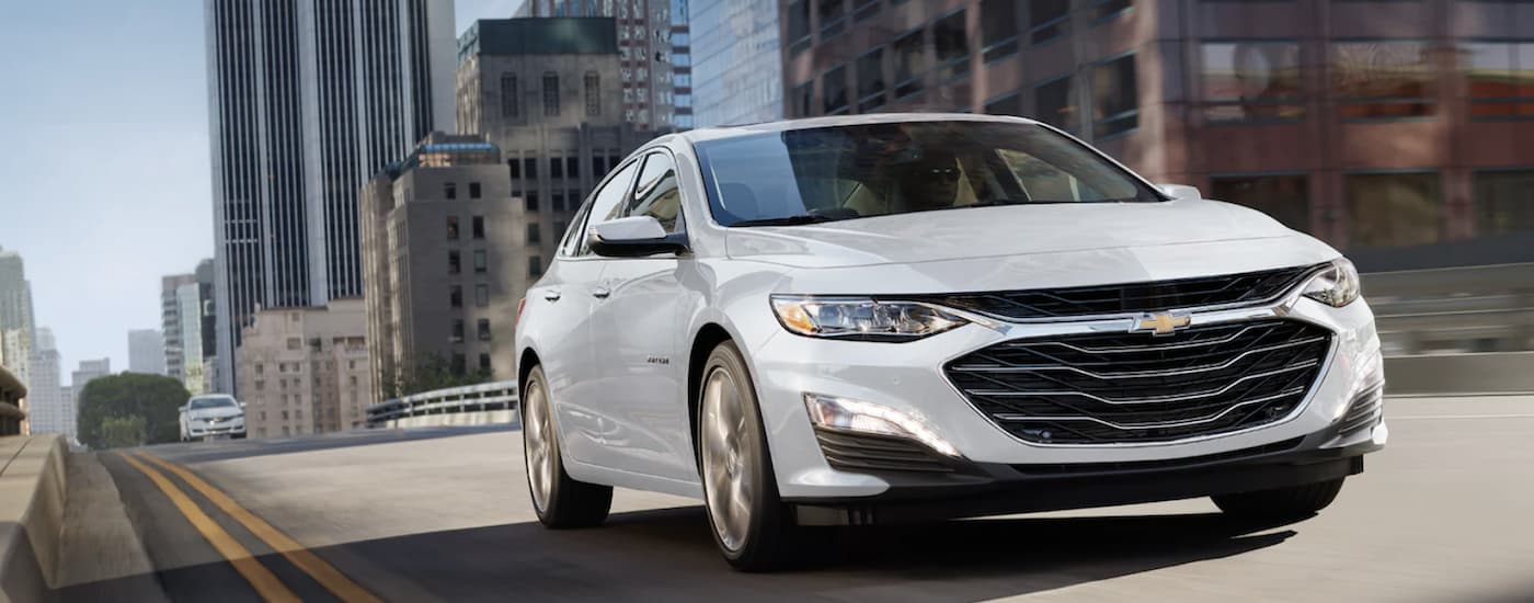 A white 2021 Chevy Malibu is shown from the front at an angle after leaving a New Albany Chevy dealer.