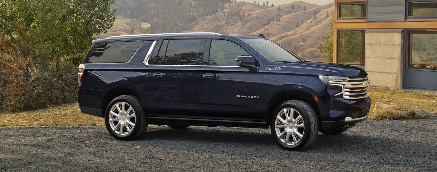 A black 2024 Chevy Suburban High Country is shown parked on a driveway and angled right after visiting a dealer with SUVs for sale.