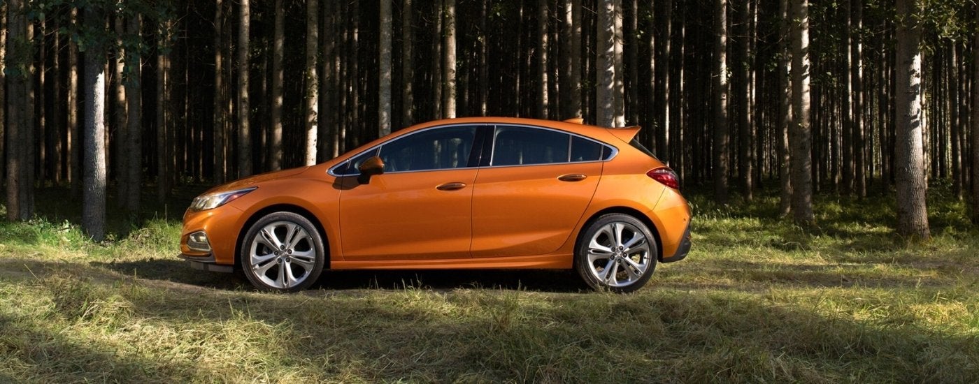 An orange 2017 Chevy Cruze is shown near trees.