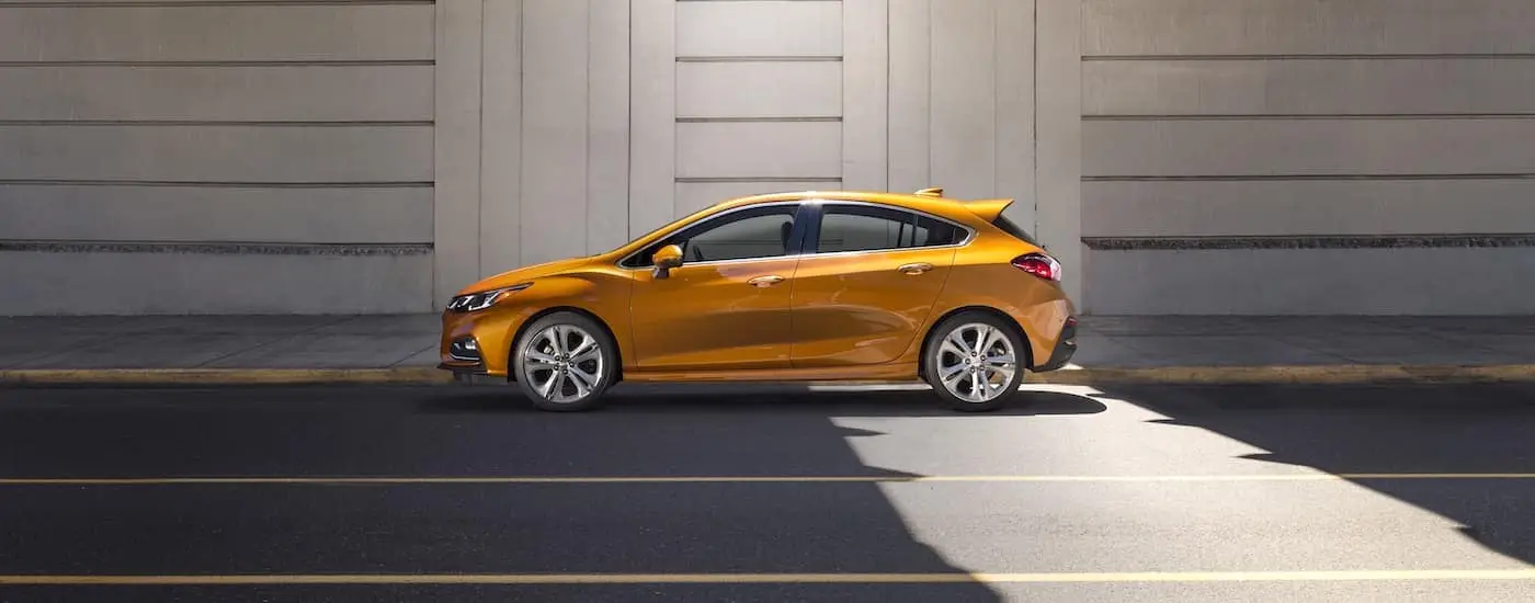 Side view of an orange 2018 Chevy Cruze parked next to a concrete wall.