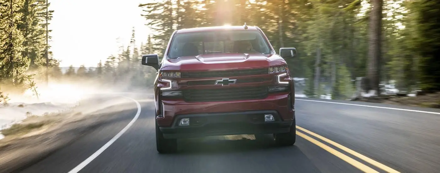 A red 2020 Chevy Silverado 1500 driving on a foggy tree-lined road.