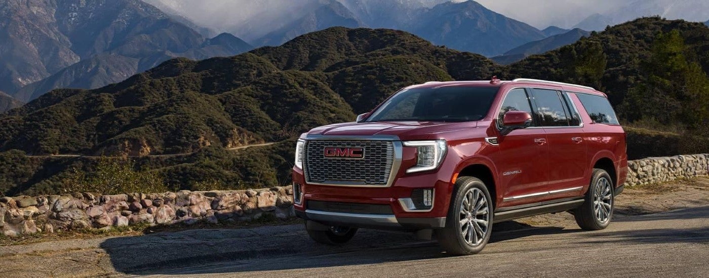 A red 2023 GMC Yukon Denali is shown parked off-road after visiting used GMC SUVs for sale.