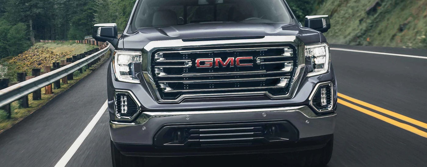 A grey used 2022 GMC Sierra 1500 is for sale is shown driving on an open road.